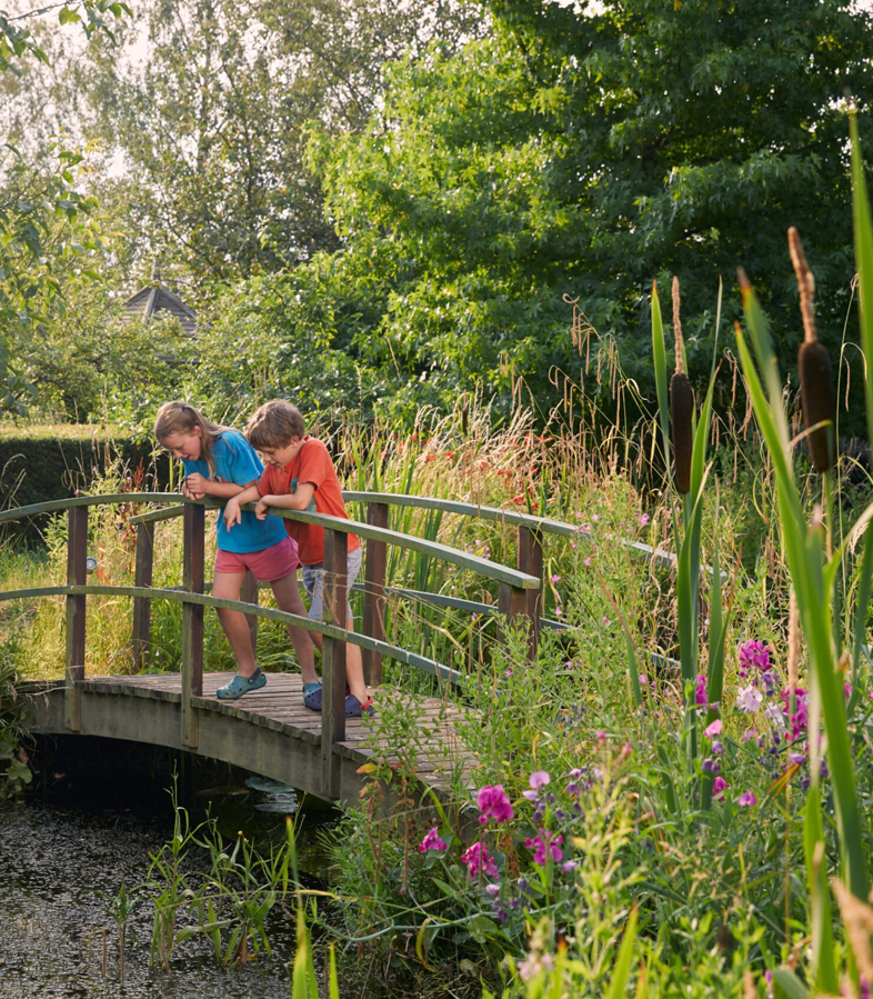 Children walking across a picturesque garden bridge